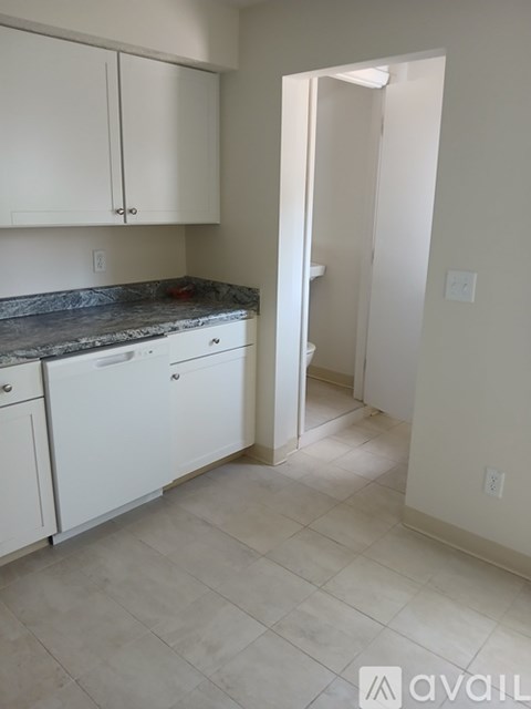 A kitchen with white cabinets and a marble countertop.