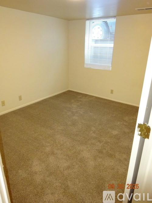 A room with a carpeted floor and a window with blinds.