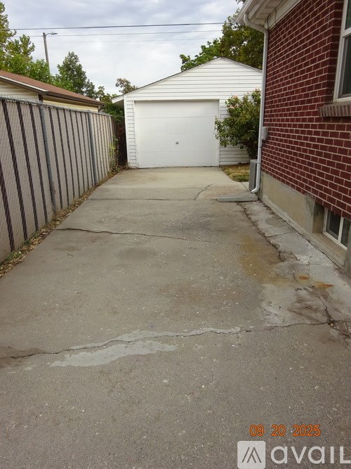 A driveway with a white garage door and a red brick building.
