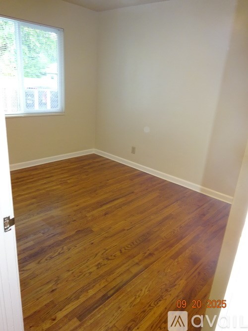 A room with wooden flooring and a window.