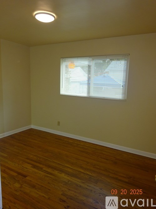 A room with wooden flooring and a window with blinds.