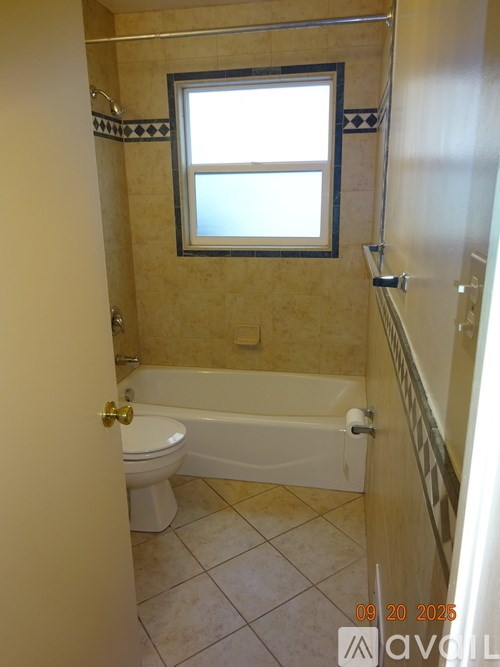 A bathroom with a toilet, tub, and window.