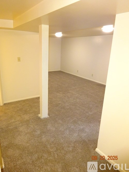 A room with a carpeted floor and white walls, with a column in the middle.