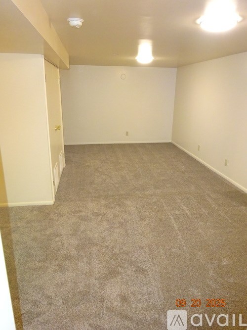 A room with a carpeted floor and a door on the left side.