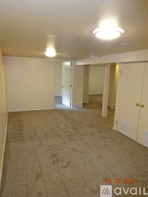 A room with carpeted floor and white walls, with a door on the right side.