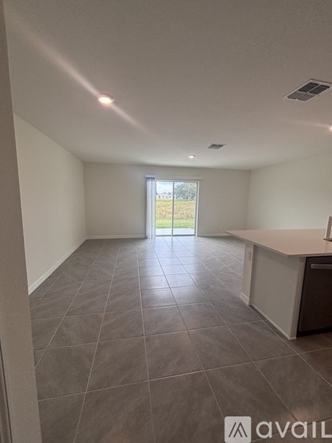 A spacious room with tiled flooring and a kitchen area.