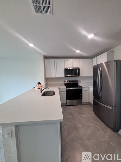 A kitchen with a stainless steel refrigerator, microwave, and oven.
