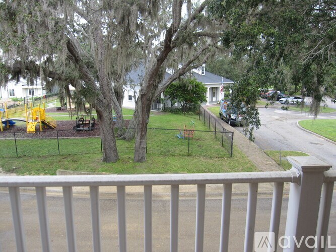 A view from a balcony overlooking a tree, a playground, and a street.