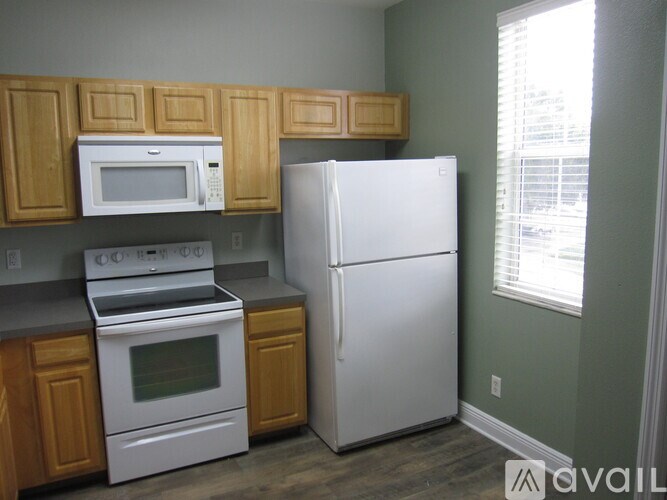 A kitchen with a white refrigerator, white stove, and white microwave.