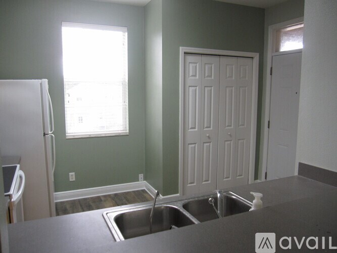 A kitchen with a white fridge, a sink and a white door.
