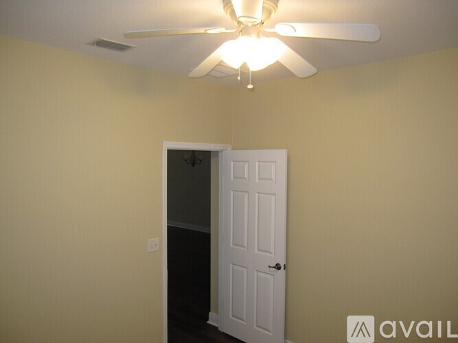 A room with a ceiling fan and a door.