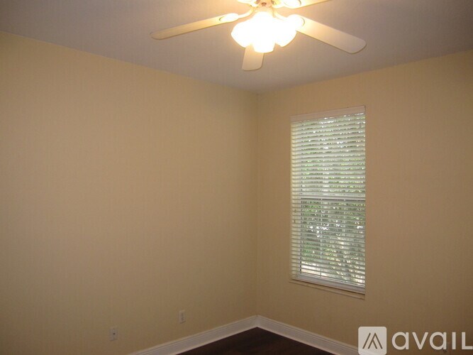 A room with a ceiling fan and a window with blinds.