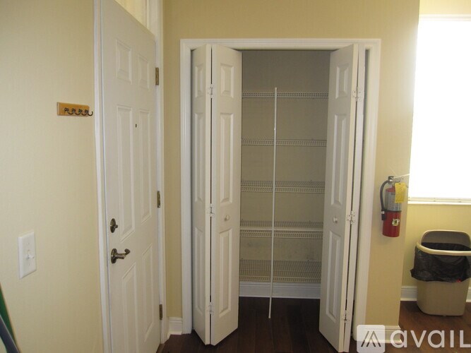 A white door is open to a room with a trash can and a fire extinguisher.