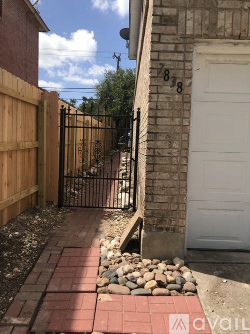 A black gate is closed and locked to a white garage door.