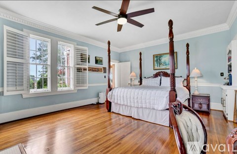 A bedroom with a four poster bed and a ceiling fan.