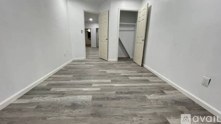 A long hallway with a wooden floor and white walls.