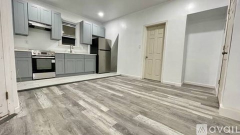 A kitchen with grey cabinets and a wooden floor.