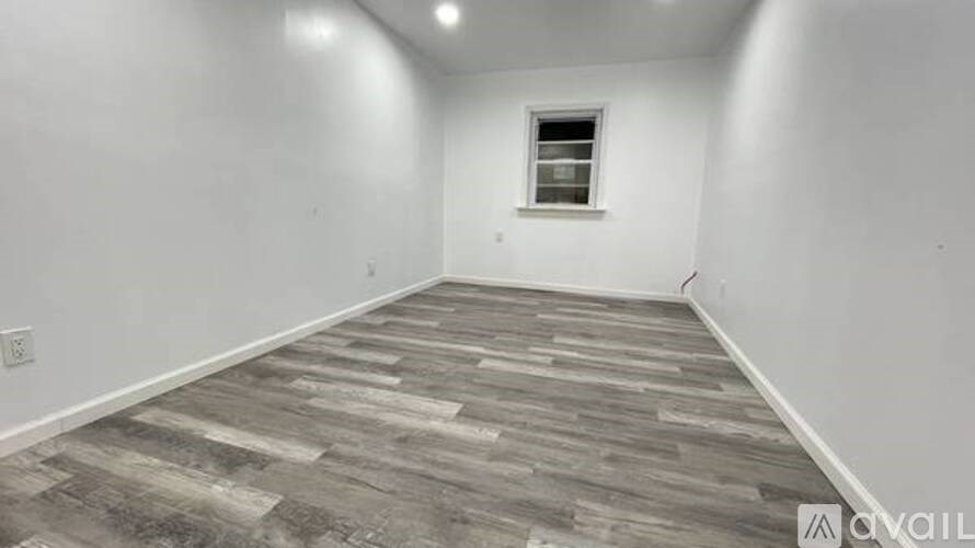 A room with wooden flooring and a window.