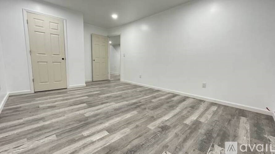 A room with wooden flooring and two doors.