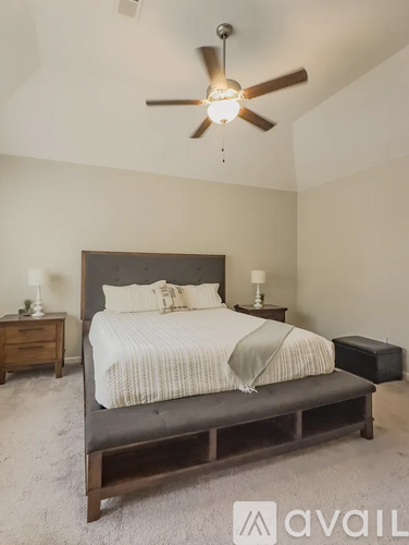 A bedroom with a large bed and a ceiling fan.
