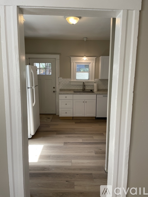 A kitchen with white cabinets and a wooden floor.