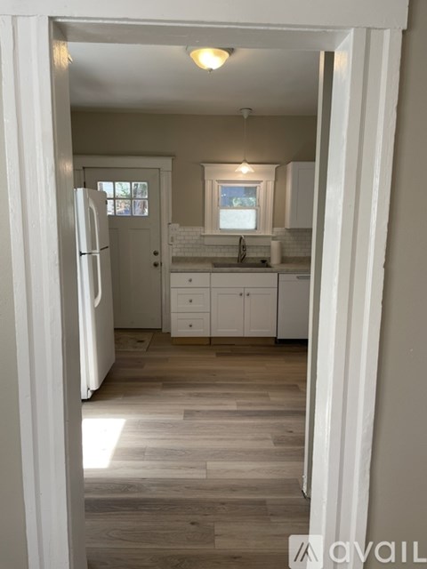 A kitchen with white cabinets and a wooden floor.