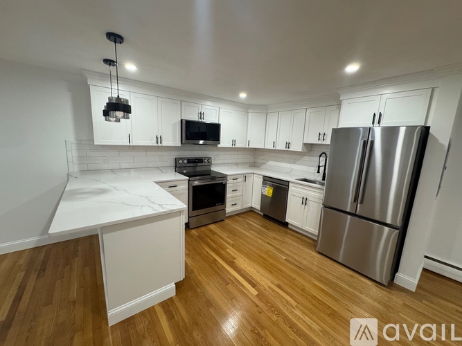 A kitchen with white cabinets and a wooden floor.