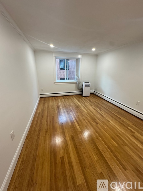 A room with wooden flooring and a window.