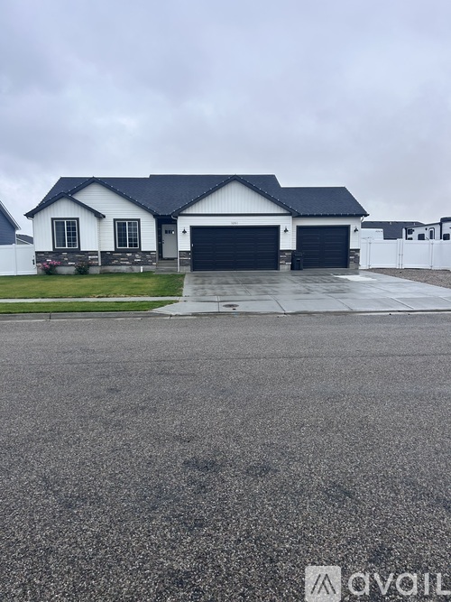 A white house with a black roof and a garage door.