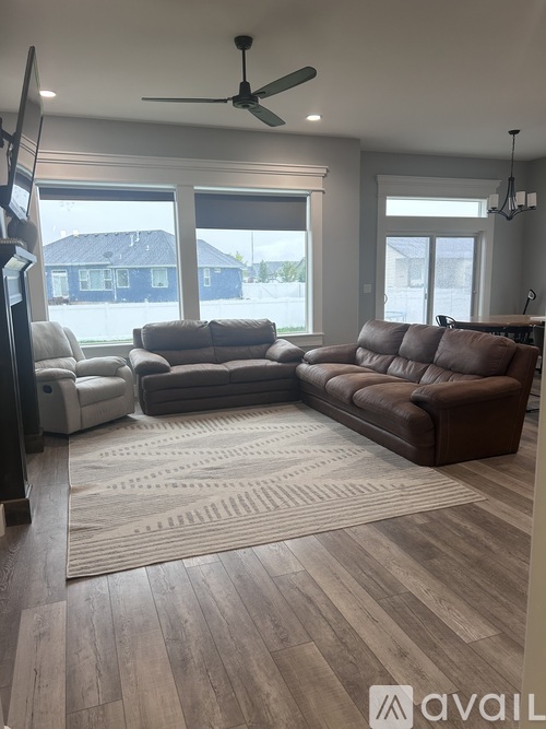 A living room with a brown couch and a white chair.