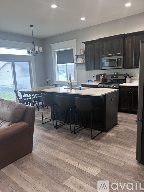 A kitchen with a brown couch and a dining table.