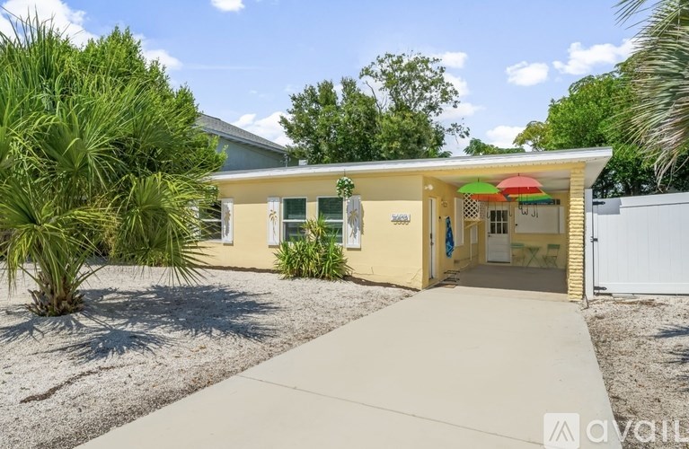 A yellow house with a white fence and a gravel driveway.