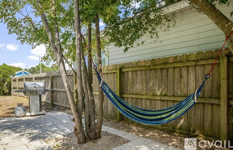 A hammock is hanging between two trees in a backyard.