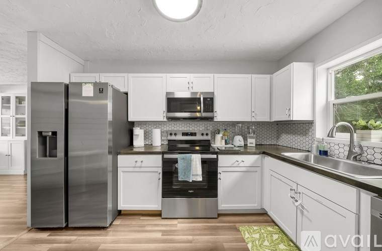 A modern kitchen with white cabinets and stainless steel appliances.