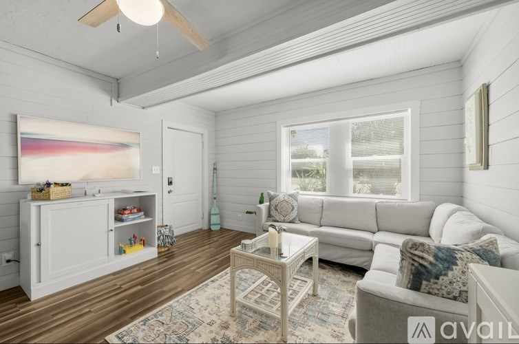 A living room with a white couch, a coffee table, and a painting on the wall.