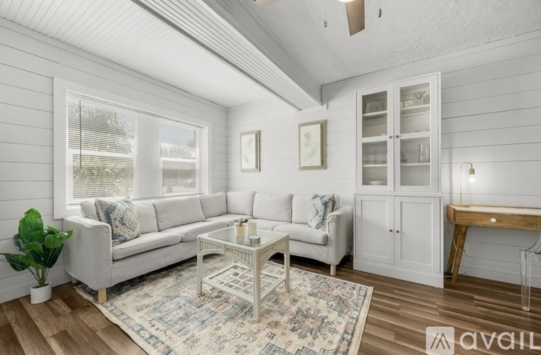 A living room with a white couch, a coffee table, and a rug.