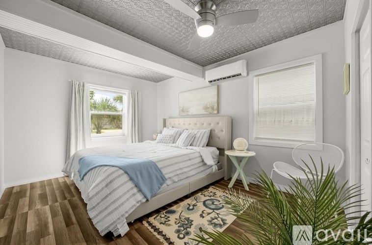 A bedroom with a bed, a small table, and a plant.