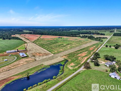 A large open field with a small lake and a few buildings.