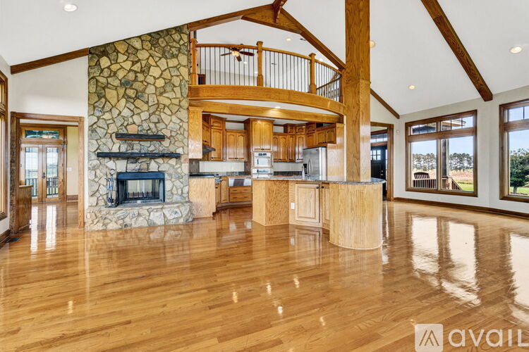 A spacious living room with wood floors and a stone fireplace.