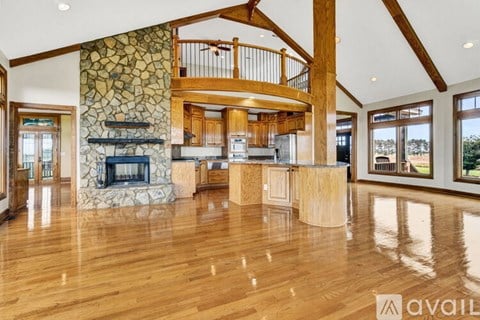 A spacious living room with wood floors and a stone fireplace.