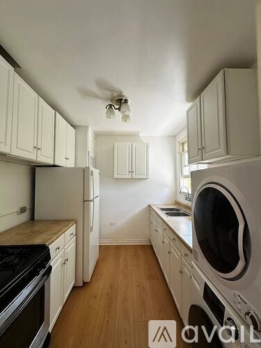 A small kitchen with white cabinets and a wooden floor.