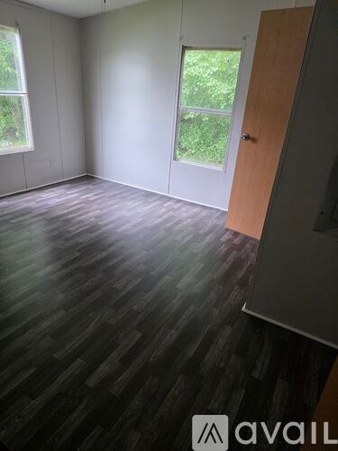 A room with wooden flooring and a door leading outside.