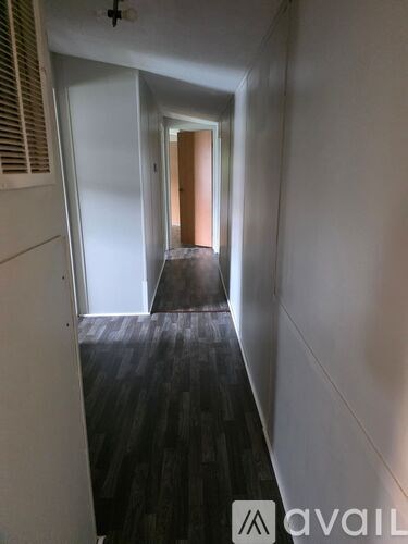 A hallway with a wooden floor and white walls.