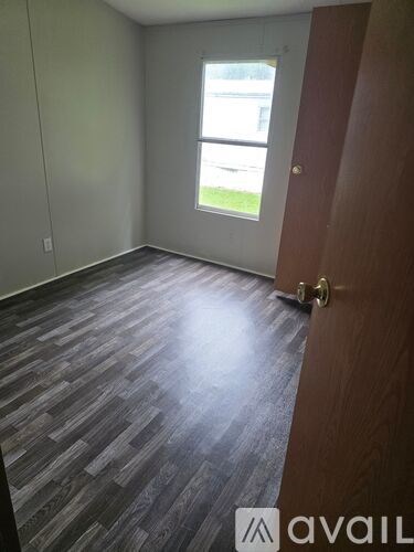 A room with a wooden floor and a door leading to a balcony.