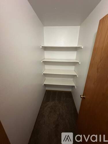 A hallway with a brown door and white walls.
