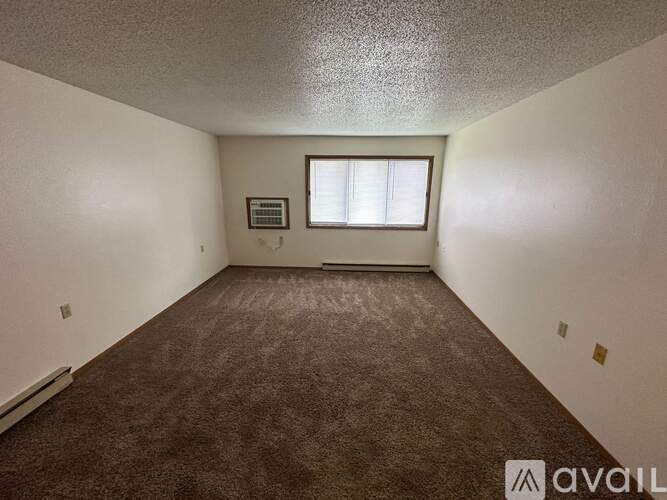A room with a carpeted floor and a window with blinds.