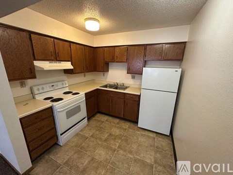 A kitchen with white appliances and brown cabinets.