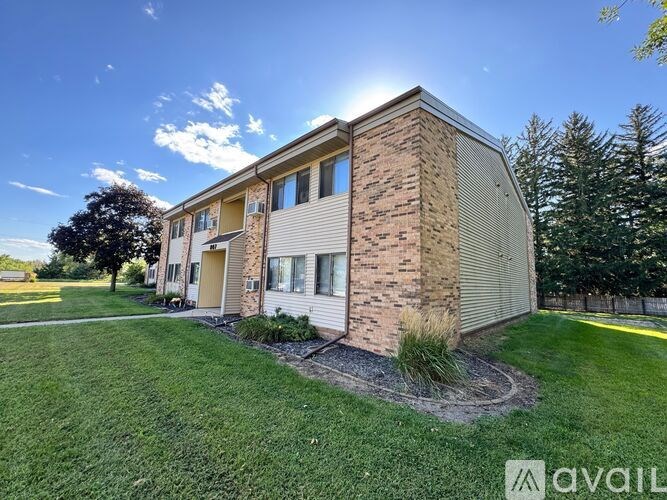 A brick house with a grassy front yard and a clear blue sky.