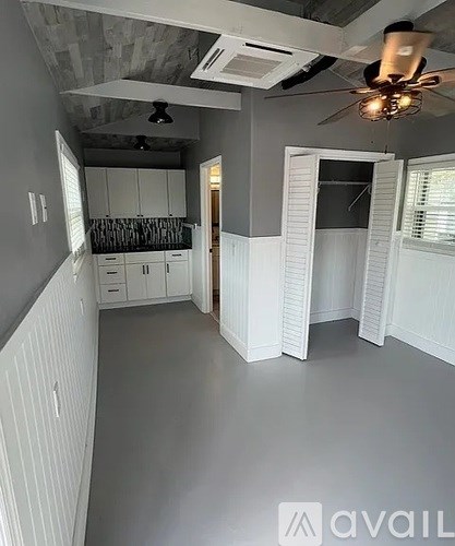 A spacious kitchen with white cabinets and a ceiling fan.
