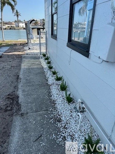 A white building with a window and a door is next to a body of water.